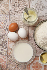 Baking ingredients for dough - white flour, eggs, milk, yeast, sugar, salt - on blue surface