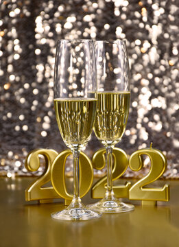Two glasses of champagne at New Year's Eve party 2022 golden shiny background stock images. Glasses of champagne and number 2022 stock photo. 2022 New Year party still life images