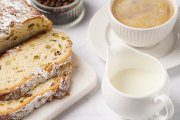 White porcelain cup with coffee cappuccino on a white saucer plate and christmas pastry stollen on a marble table