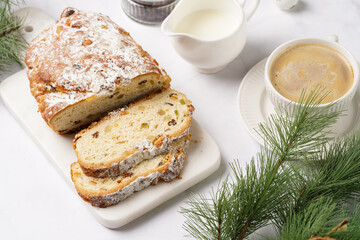 White porcelain cup with coffee cappuccino on a white saucer plate and christmas pastry stollen on a marble table