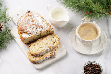 White porcelain cup with coffee cappuccino on a white saucer plate and christmas pastry stollen on a marble table