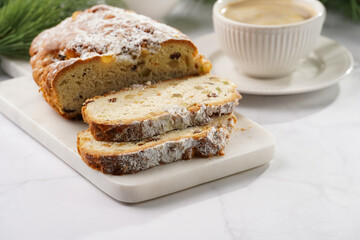 White porcelain cup with coffee cappuccino on a white saucer plate and christmas pastry stollen on a marble table