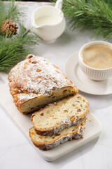 White porcelain cup with coffee cappuccino on a white saucer plate and christmas pastry stollen on a marble table