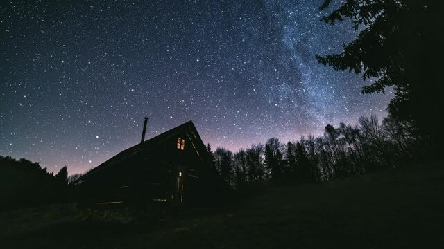 Time lapse Fairytale night sky with millions stars of milky way galaxy above wooden hut in wild forest nature Astronomy