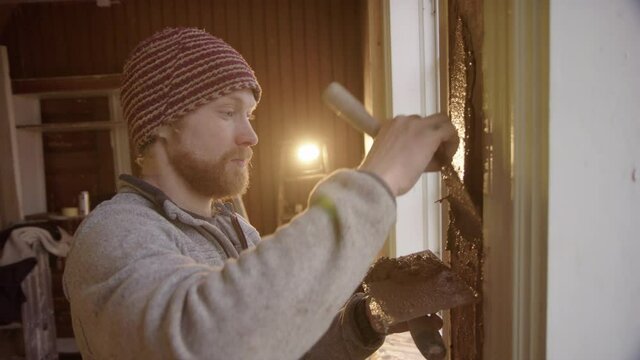 MS BACKLIT - A handsome professional plasterer applies clay to a window column