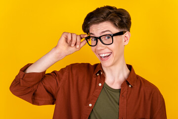 Photo of young cheerful man confident hand touch eyeglasses vision isolated over yellow color background