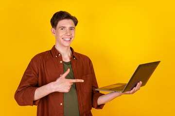 Photo of young man indicate finger laptop ad promotion select discount isolated over yellow color...