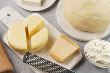 Various cheese types on marble and porcelain plates and fresh dough - ingredients for traditional georgian open pie khachapuri