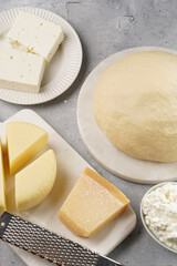 Various cheese types on marble and porcelain plates and fresh dough - ingredients for traditional georgian open pie khachapuri
