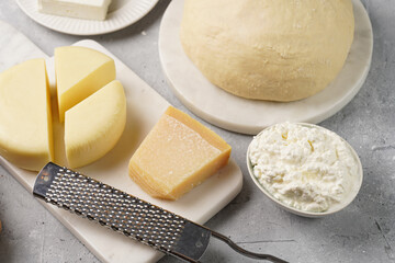 Various cheese types on marble and porcelain plates and fresh dough - ingredients for traditional georgian open pie khachapuri