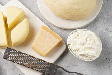 Various cheese types on marble and porcelain plates and fresh dough - ingredients for traditional georgian open pie khachapuri