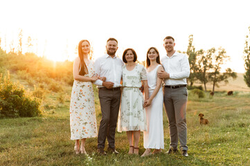 Fototapeta premium portrait of a beautiful family. daughter with mom and son with sister and father together. a group of people of different ages are happy. family walk at sunset day in summer.