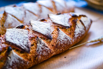 Homemade whole grain bread with notches, french baguette  with sourdough on a dark background, copy space. Craft bread background 