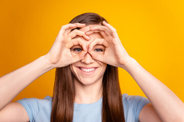 Photo of young cheerful lovely lady see eyeglasses binoculars have fun isolated over yellow color background