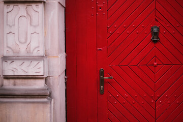 closed wooden red door in a beautiful old house in the city center close-up. Door lock in wooden door exterior of vintage house