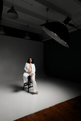 Caucasian young beautiful pregnant woman with dark hair in a white fashionable elegant pantsuit posing on a white background. isolates the banner space for text. Fashion for pregnant women. A business