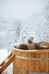 Fotobehang Woman relaxing in hot bath outdoors, sitting back and enjoying beautiful view on snowy mountains. Winter holidays in the mountains, hot water treatments concept. Caucasian woman wearing winter hat © rh2010