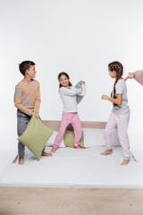 Naklejka premium happy kids having pillow fight while standing isolated on white.