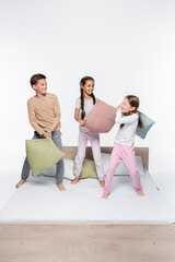 Obraz premium cheerful kids having pillow fight while standing on white.