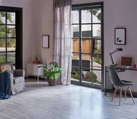 Modern rom with working table and armchair style, parquet floor, frame lamp decor, curtain, garden view house interior.
