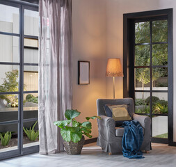 Modern home corner decoration with armchair pillow and blanket style, garden view, vase of plant, interior decor.