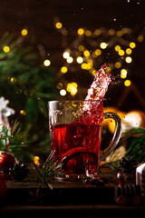 red tea in a glass splashes up due to the fact that a strainer with tea leaves falls into it.