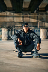 Skater male relax sitting on skateboard on street urban background