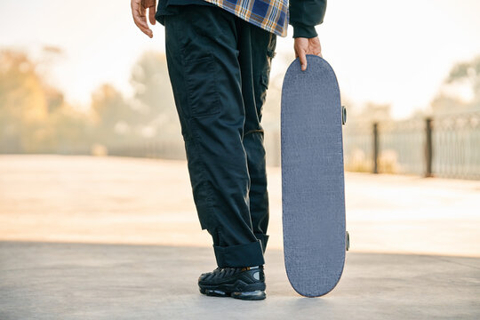 Cropped image of skater holding skateboard on the street