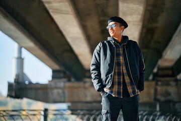 Portrait of young trendy man posing on urban street background