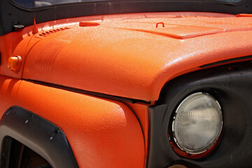 Headlight lamp vintage car. Classic car headlight. Close-up of headlights of orange vintage car. Exhibition.Car body protective coating..