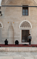 Three people are praying in the courtyard of the mosque. Back view photo. 