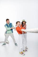 preteen children pulling rope while playing tug of war game on white.