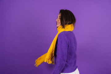 Young woman in a purple soft cozy sweater and a yellow scarf with makeup cheerful smiling, in a good mood with a radiant smile