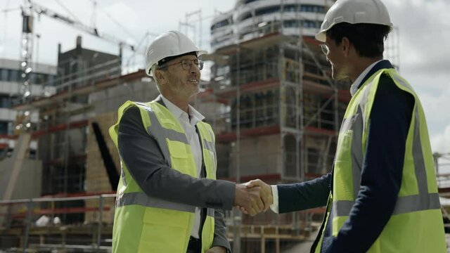 Two men standing on construction site and shaking hands