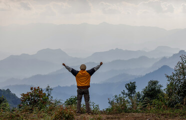 Male hiker with arms up enjoying spectacular layered mountain ranges in thailand