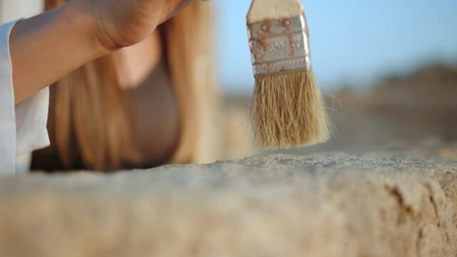 Archeological Excavation. Hand of Archaeologist With Tools (Brush) Sweep. Archaeological Digging Site: Great Female Archeologist Work on Excavation Site, Cleaning Cultural Artifacts with Brush.
