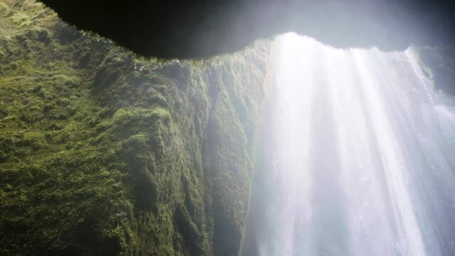 Low angle view of the waterfall, slow motion shot of water flow from the waterfall, evaporation of water and moisture droplets
