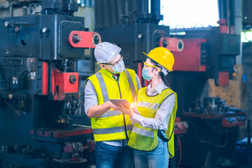 white and yellow helmet engineer discuss about how to fix and maintain machine in industial factory