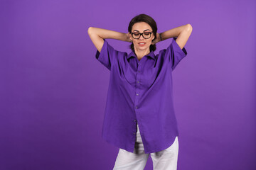 Young woman in a shirt with short sleeves on a purple background, with makeup, lipstick on her lips and stylish glasses posing on the background