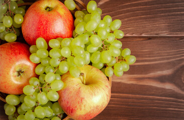 Ripe apples and grapes on a wooden table.