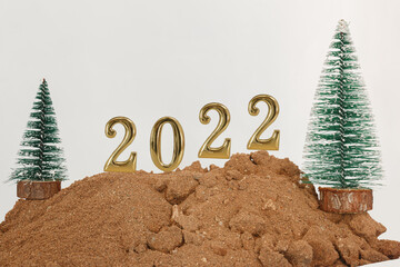 Concept  happy new year 2022  on floor sand ,and christmas tree with white background