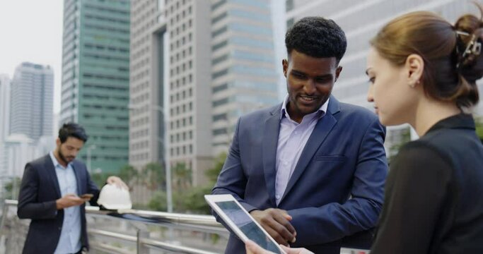African American businessman advise plan strategy work to colleagues with sincerity and friendship smile stand in city. Salesman service products to female customer with enthusiasm with tablet.