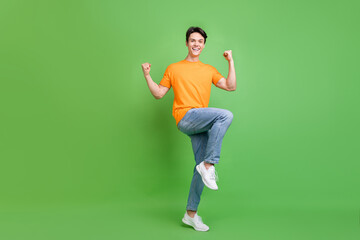 Fototapeta na wymiar Full size photo of cheerful happy young man winner rise fists good mood isolated on green color background