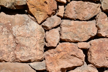 Background, texture of stone. The wall is made of large, untreated stones.