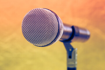 Close-up microphone attached to the microphone stand. Metal mesh mesh on speech surface in selective focus. Selective focus with blurred background. Music, art, entertainment, technology concept.