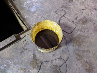 old dirty bucket with used engine oil in the garage.