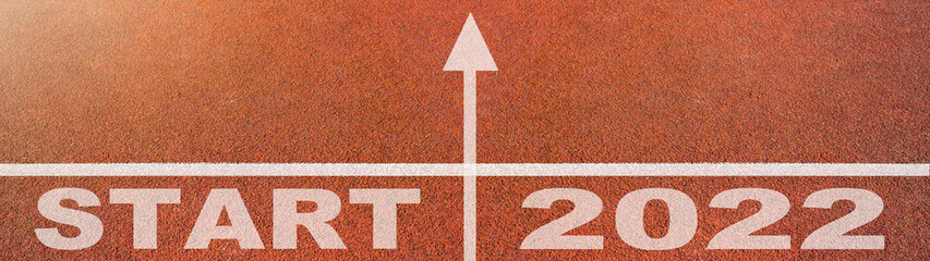 New year 2022 or start straight concept background banner panorama. Word START 2022 written on the orange running track on sports field, top view