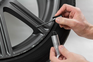 The hand painting the car wheel with a brush. Close up. Isolated on a white background