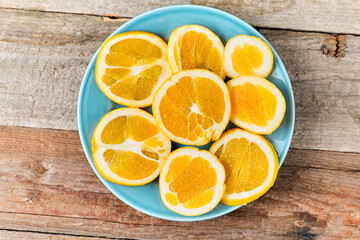 Blue plate with fresh oranges cut in halves, top view
