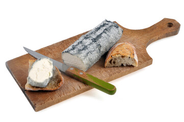Bûche de fromage de chèvre cendrée sur une planche à découper avec un couteau et du pain sur fond blanc